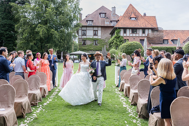 Binnenkomst van de bruid met vader tijdens ceremonie met klappende gasten bij La Butte Aux Bois Lanaken